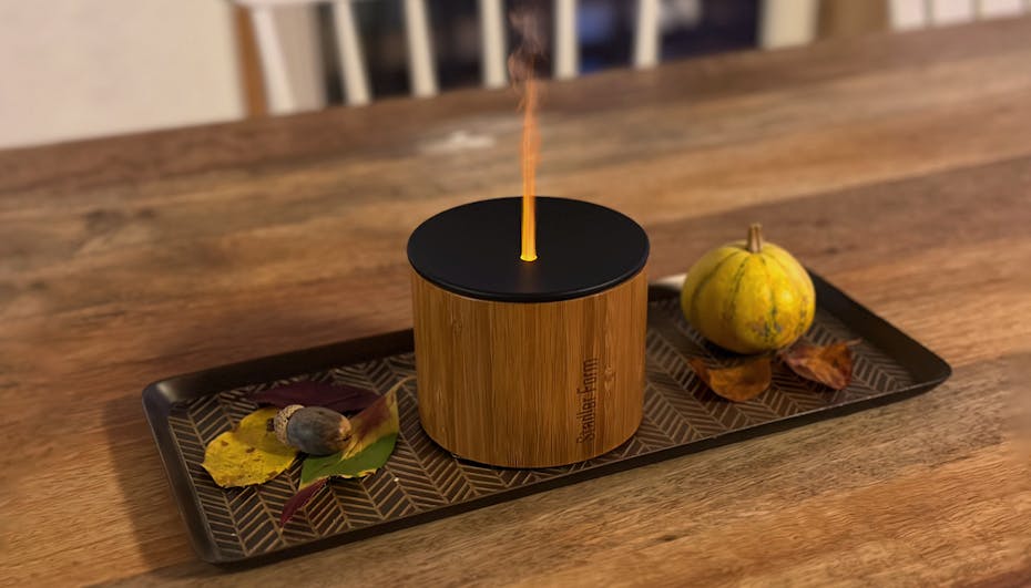 Nora aroma diffuser from Stadler Form on a sideboard with books and a plant