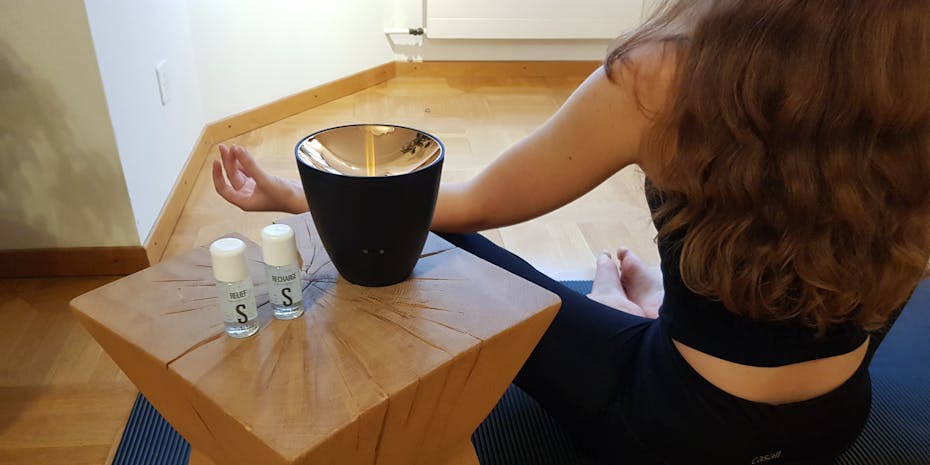Woman does yoga next to a Zoe aroma diffuser by Stadler Form with essential oils