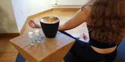 Frau macht Yoga neben einem Zoe Aroma-Diffuser von Stadler Form mit ätherischen Ölen.