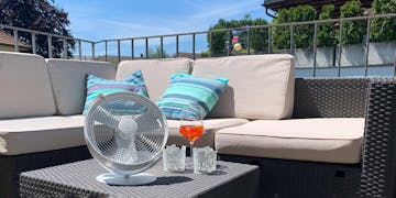 Tim Tischventilator in Weiß von Stadler Form an einem Sommertag auf einem Balkon