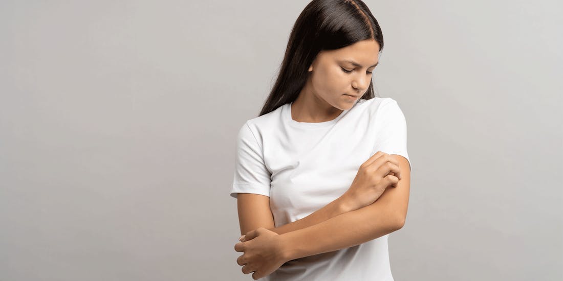 Young woman scratches her arm Young woman scratches her arm