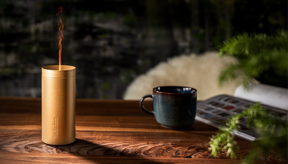 Lucy Aroma diffuser in gold from Stadler Form on a table with coffee