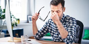 Man im Büro mit brennenden Augen Symbolic image for poor air quality at the workplace