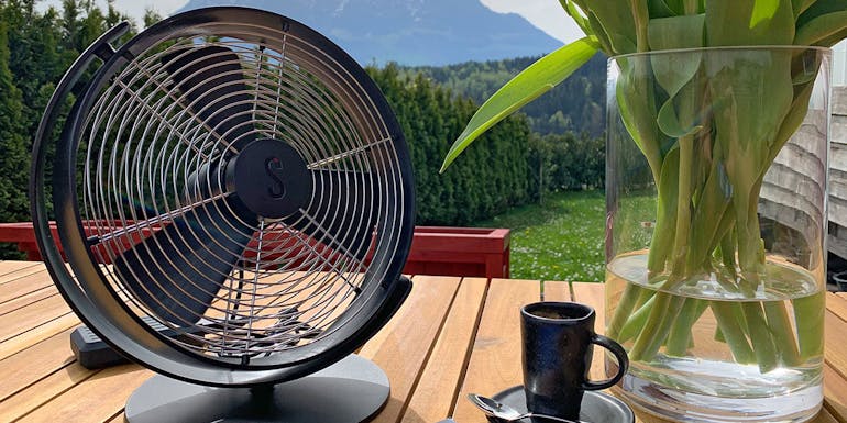 Tim Tischventilator in Schwarz von Stadler Form auf einem Tisch auf einer Gartenterrasse Tim Tischventilator in Schwarz von Stadler Form auf einem Tisch auf einer Gartenterrasse