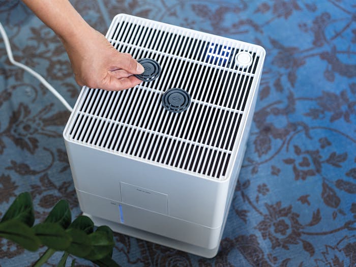 A hand places a fragrance pin Black Orchid on Oskar humidifier from Stadler Form