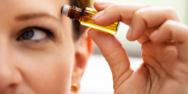 Woman rubs essential oil on her temple Woman rubs essential oil on her temple