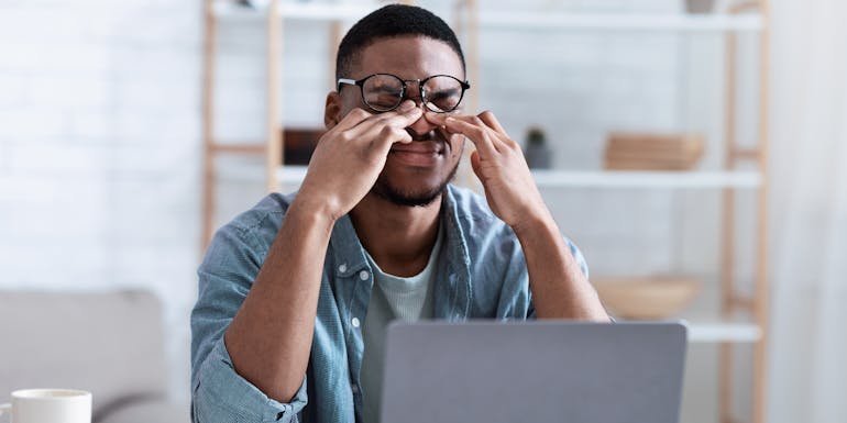 Man mit juckenden Augen bei der Arbeit Man mit juckenden Augen bei der Arbeit