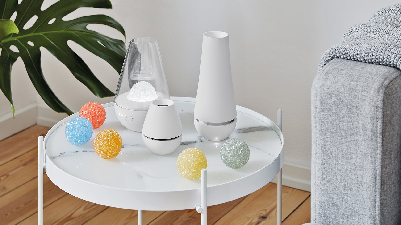 Lina, Nina and Tima aroma diffuser with fragrance globes by Stadler Form on a side table next to a sofa