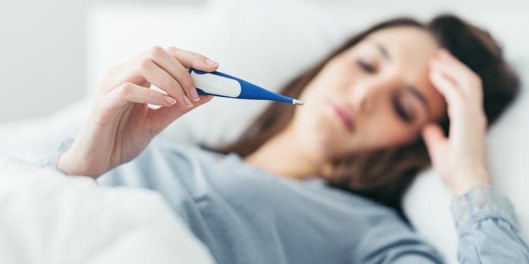 Woman sick in bed with thermometer Woman sick in bed with thermometer