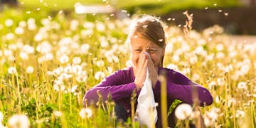 Girl with allergy sits in a flower meadow