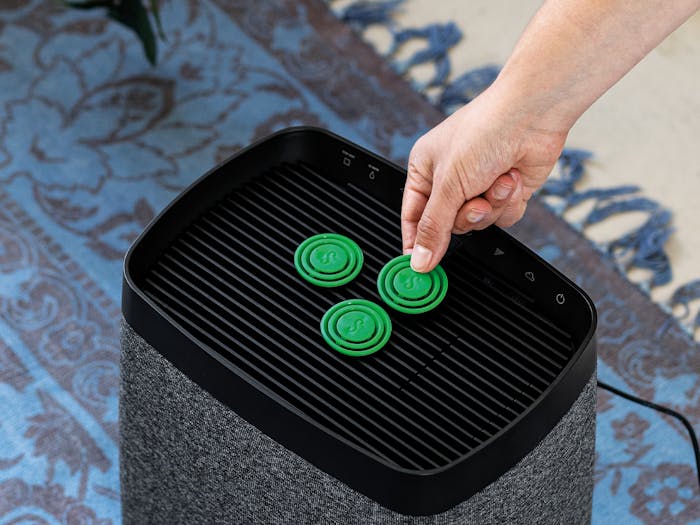 A hand places a fragrance pin Green Forest on Karl humidifier from Stadler Form