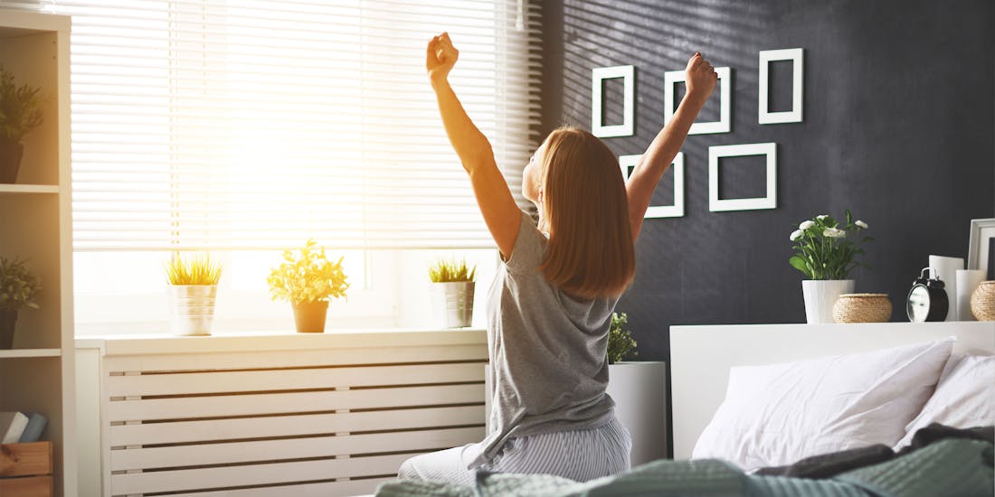 Frau, die sich morgens im Schlafzimmer streckt Frau, die sich morgens im Schlafzimmer streckt