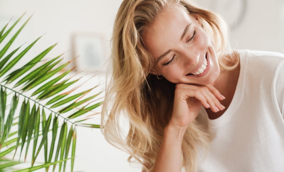 Stadler Form glückliche Gesichter blonde Frau lächelt neben einer grünen Pflanze