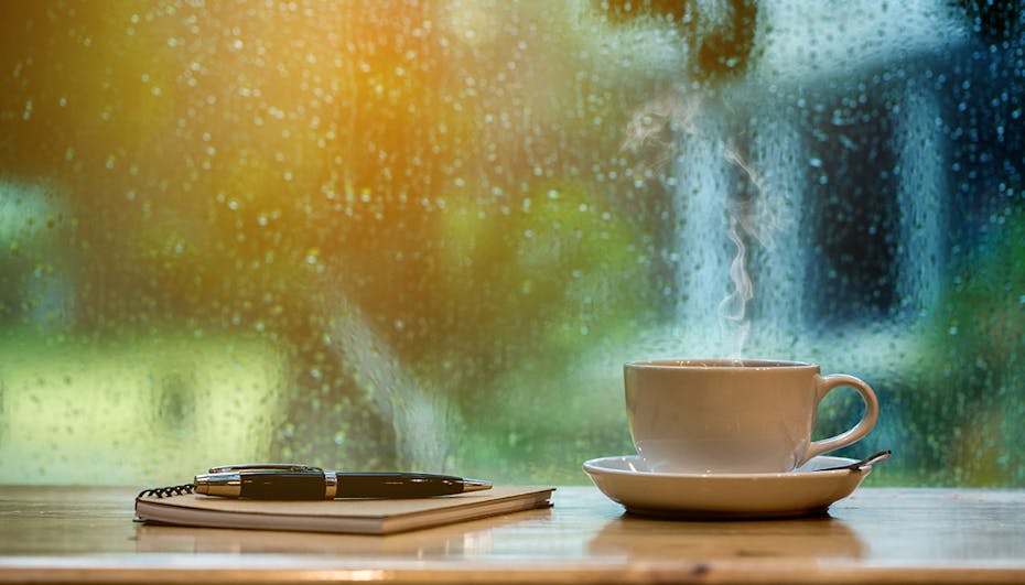 Stift und Tasse Tee mit regnerischem Wetter im Hintergrund Stift und Tasse Tee mit regnerischem Wetter im Hintergrund