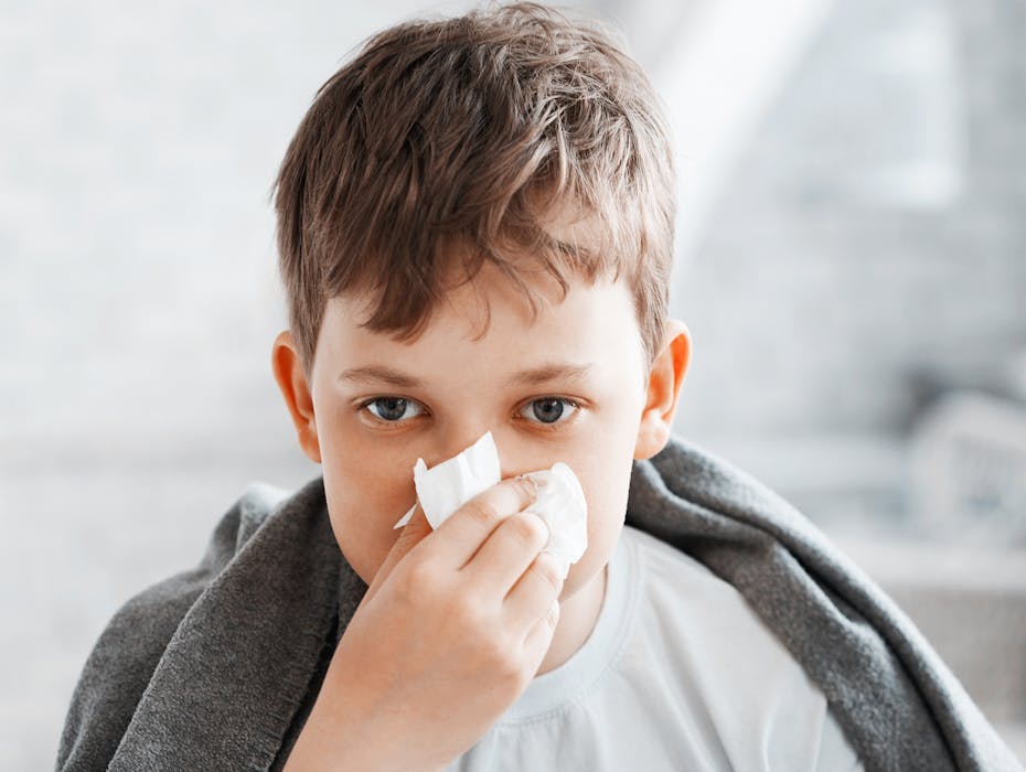 Boy with a cold blowing his nose as symbolic image for colds during winter time