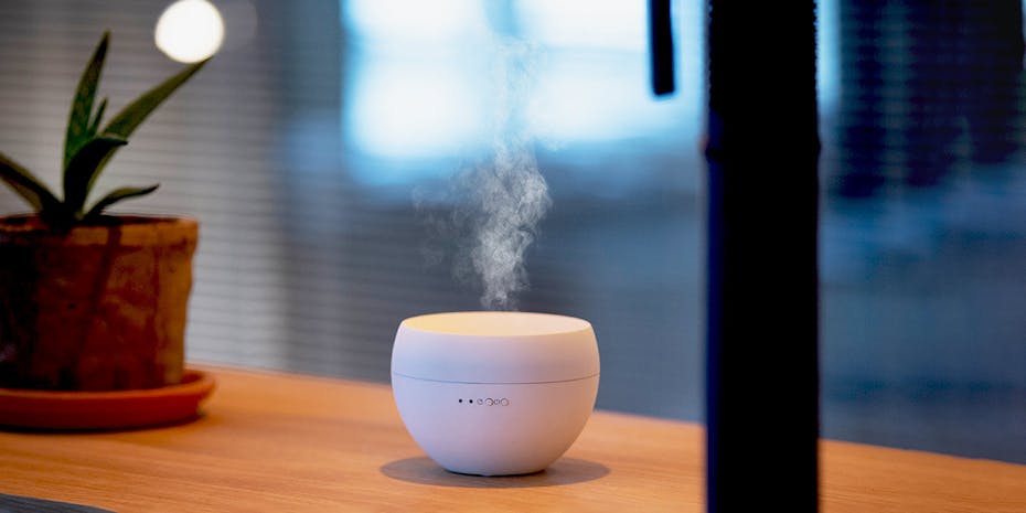 Aroma diffuser Jasmine in white with visible mist output by Stadler Form with a plant in the background Aroma diffuser Jasmine in white with visible mist output by Stadler Form with a plant in the background