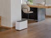 Noah Pro humidifier by Stadler Form in a large, open living area between the coat rack, dining table, and seating area.