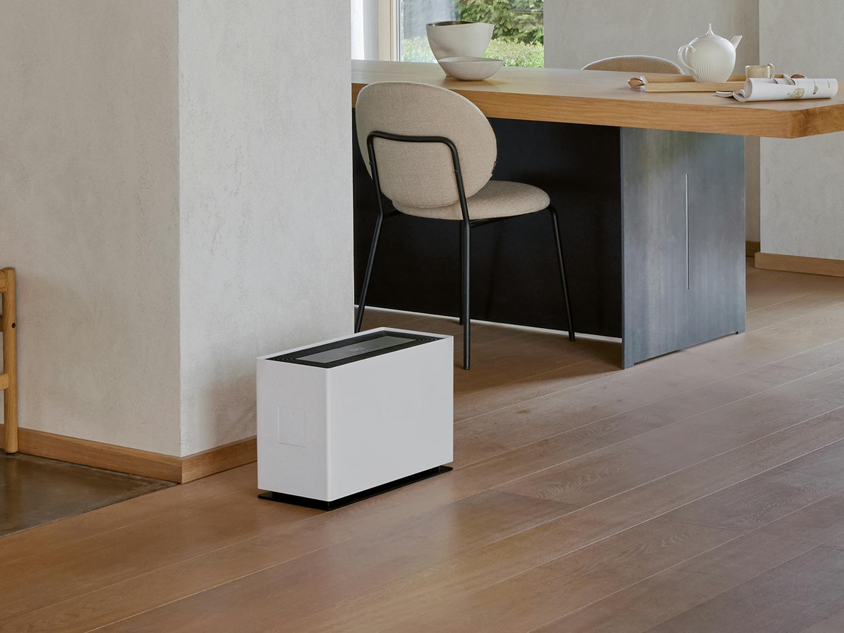 Noah Pro humidifier by Stadler Form in a large, open living area between the coat rack, dining table, and seating area.