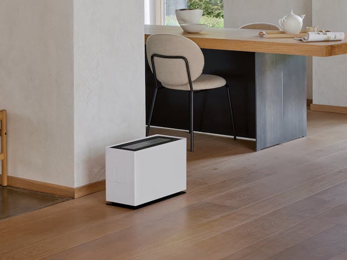 Noah Pro humidifier by Stadler Form in a large, open living area between the coat rack, dining table, and seating area.