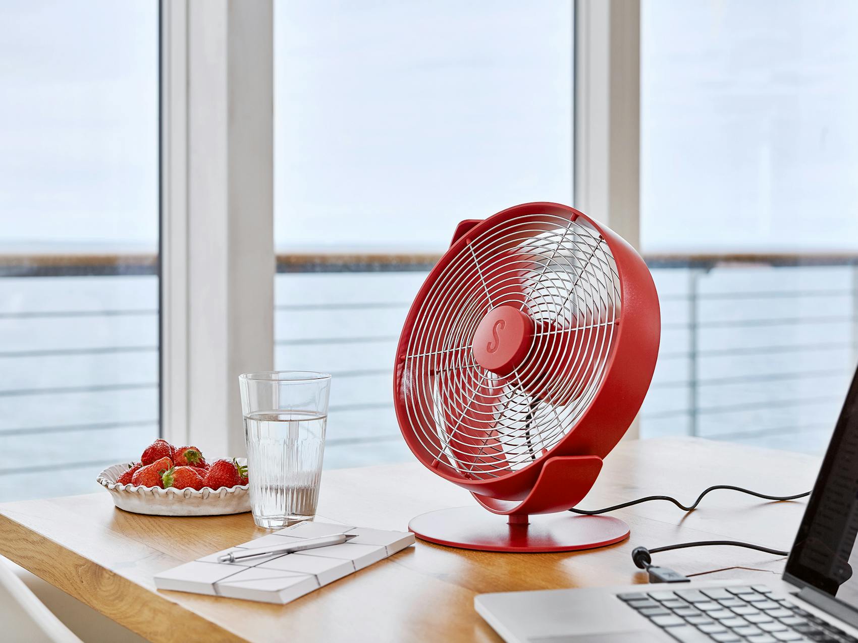 Tim table fan by Stadler Form in chili red on a homeoffice desk