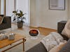 Erik fan heater with flame effect by Stadler Form next to a sofa