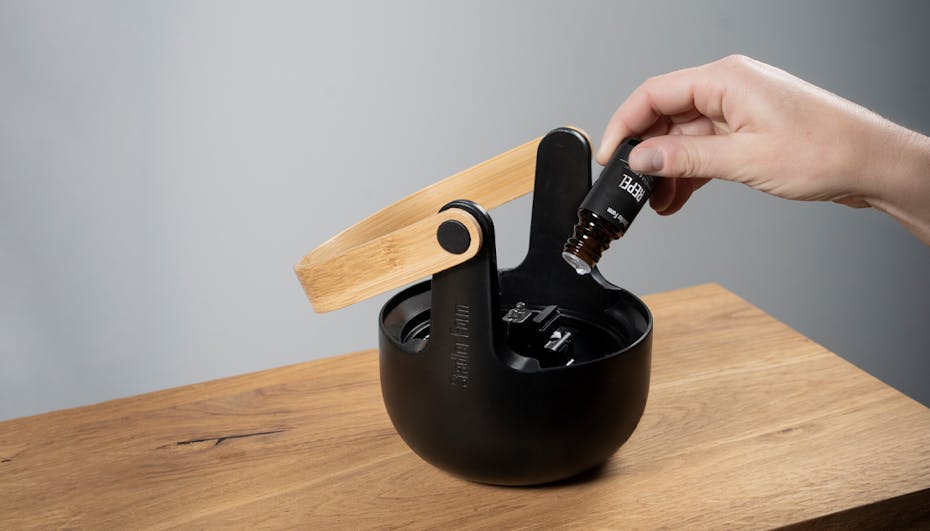 Nahaufnahme des Wassertanks von Sophie, dem Aroma-Diffusor von Stadler Form, eine Hand tropft ätherisches Öl Repel von Stadler Form hinein. Nahaufnahme des Wassertanks von Sophie, dem Aroma-Diffusor von Stadler Form, eine Hand tropft ätherisches Öl Repel von Stadler Form hinein.